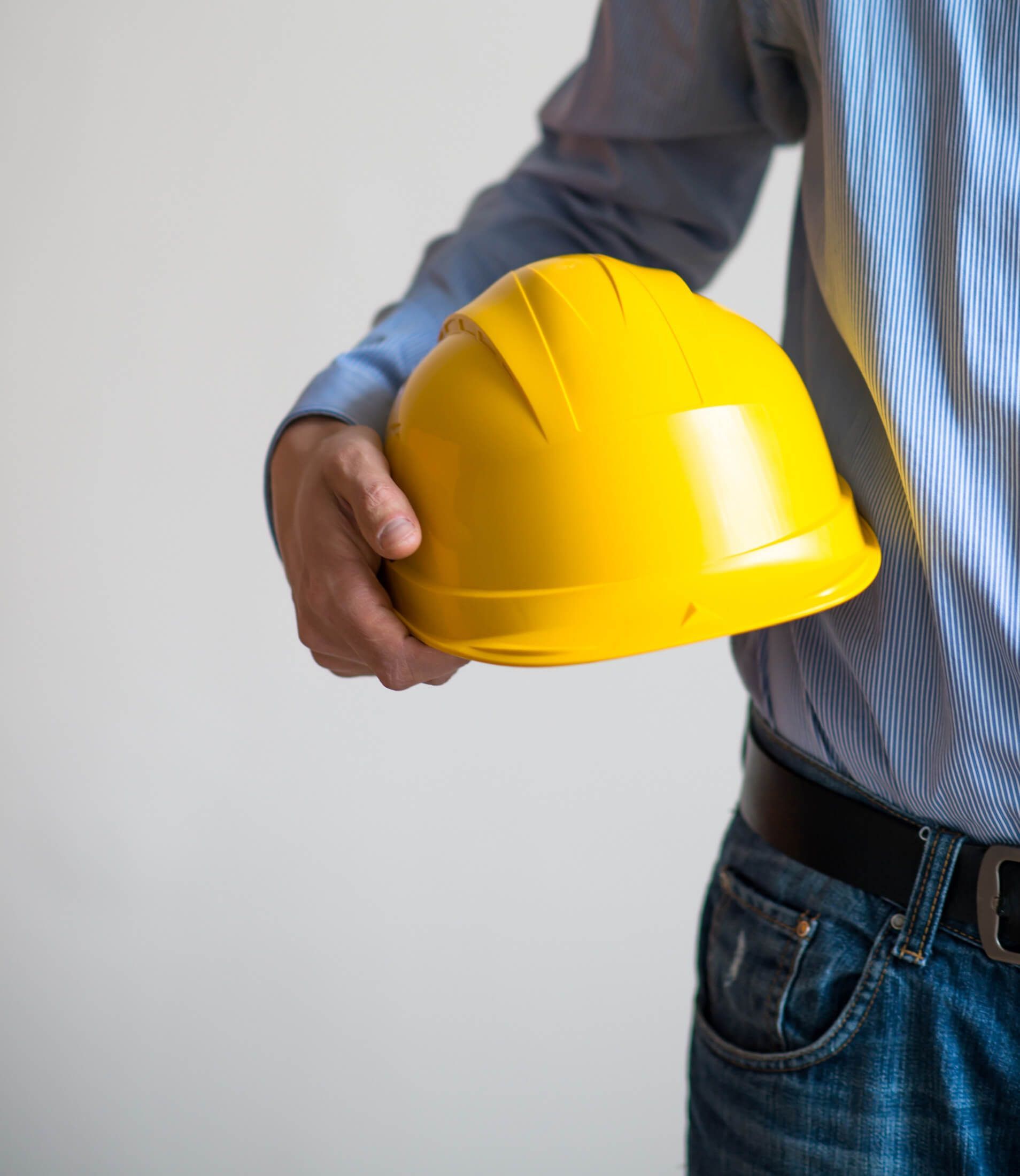 Un hombre sostiene un casco amarillo en su mano.