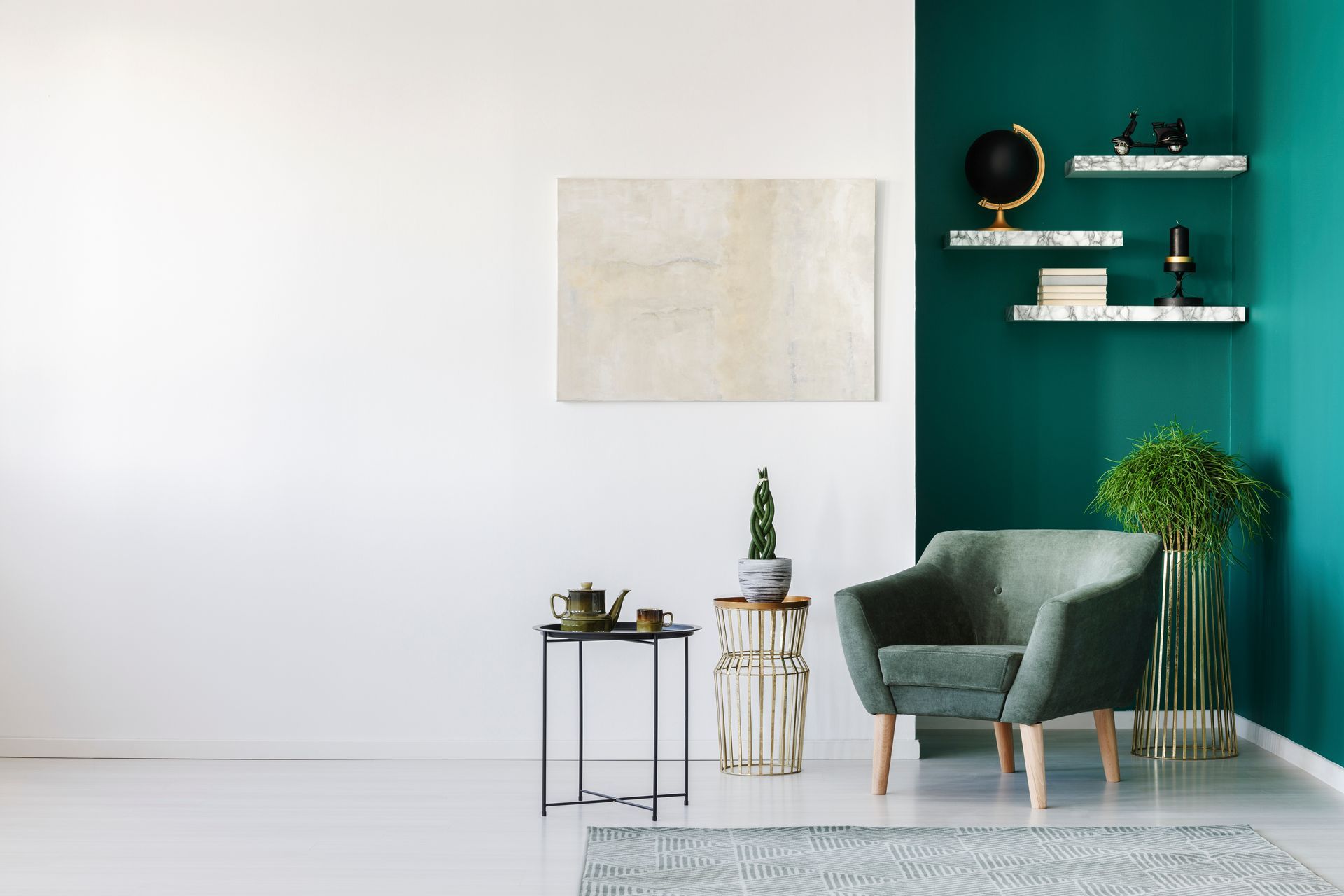 Un fauteuil vert, une petite table avec un service à thé, des plantes et des étagères sur des murs blancs et turquoise.