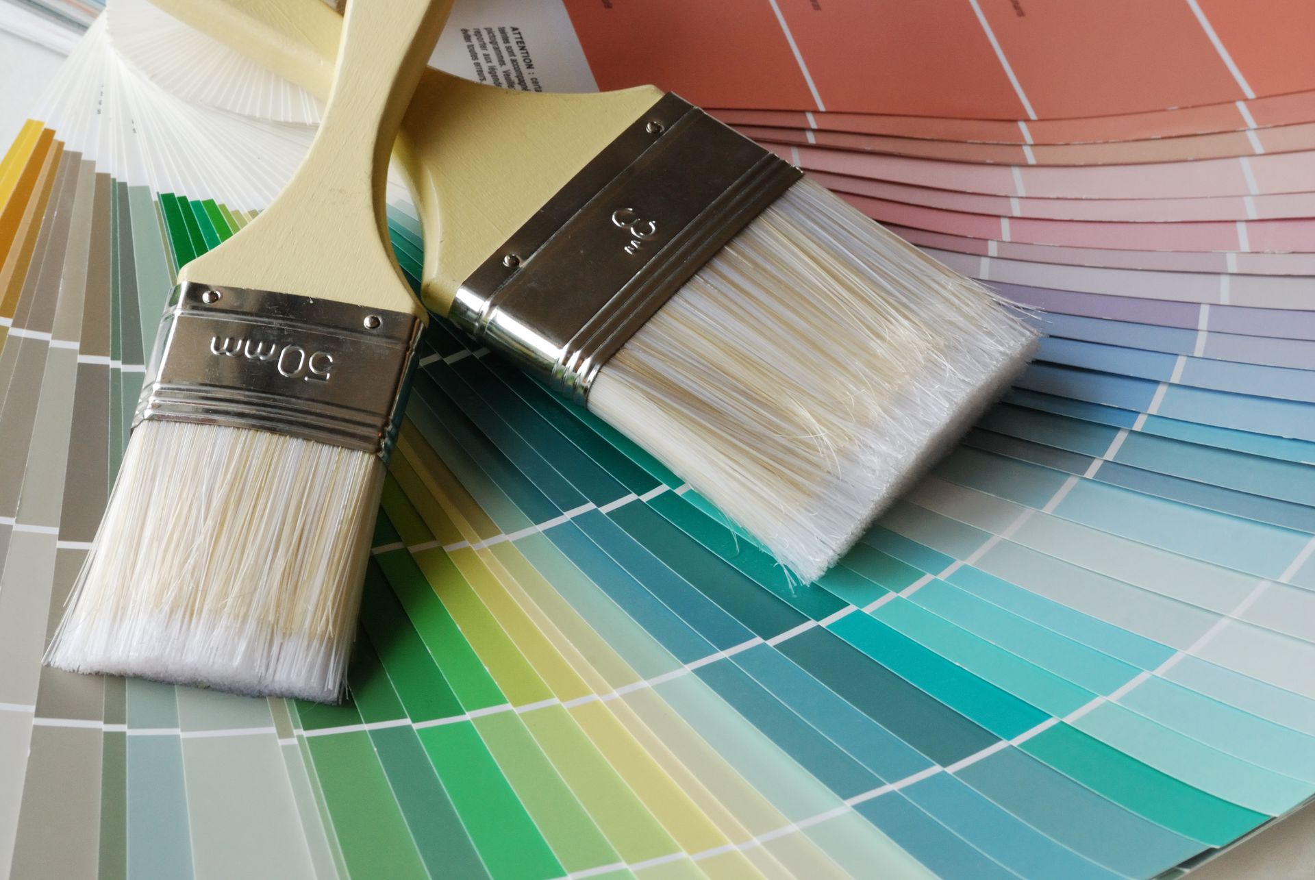 Deux pinceaux sur un nuancier présentant une gamme de couleurs.