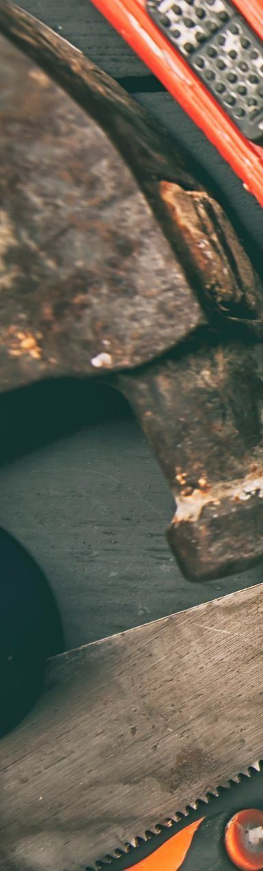 Gros plan sur une scie à main rouillée et d'autres outils, certains peints en orange.