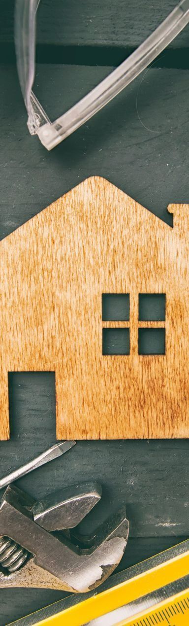 Découpe en bois d'une maison avec des outils, notamment des lunettes de sécurité, une clé et un niveau.