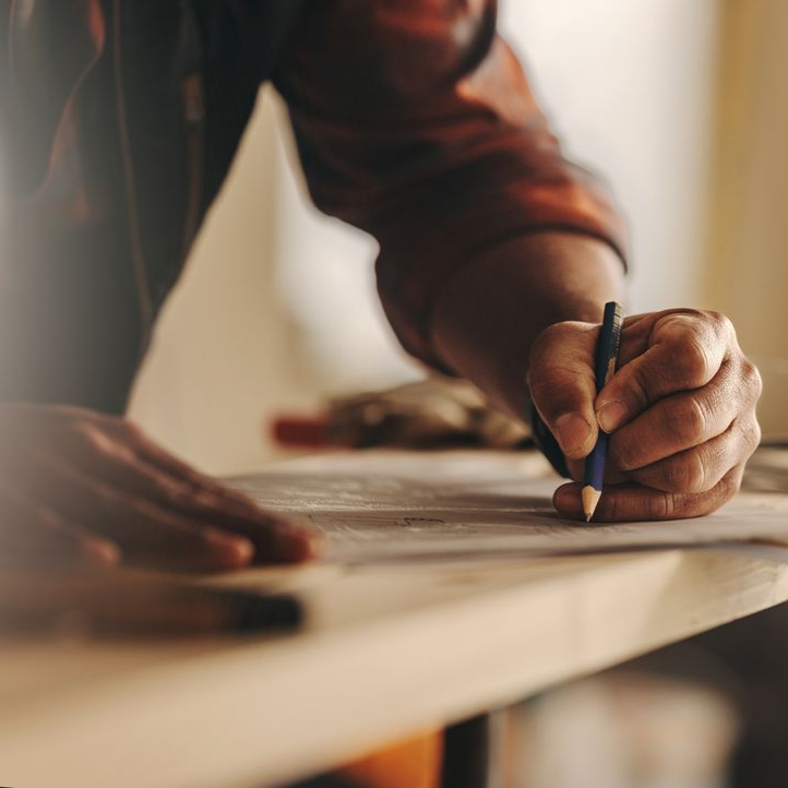 Écriture manuscrite au stylo sur du papier posé sur une surface en bois clair.