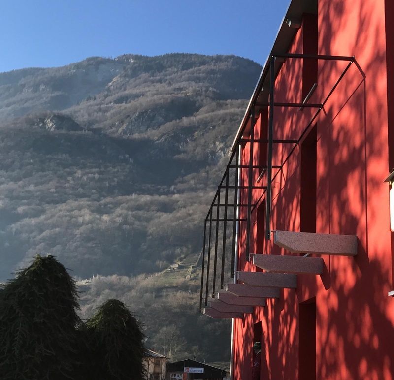 Casa rossa con inferriate nere e vista sulla collina