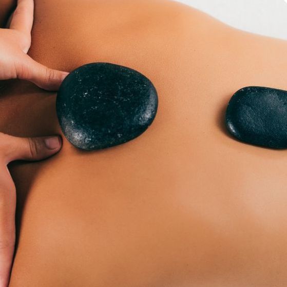 Una mujer está recibiendo un masaje con piedras calientes en la espalda.
