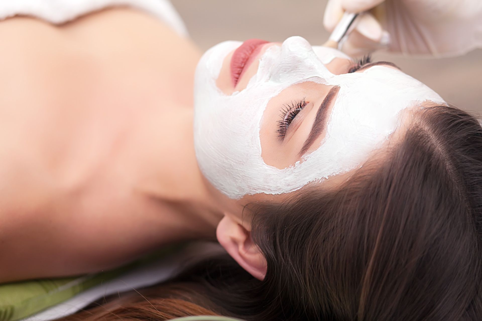 Una mujer se pone una mascarilla blanca en la cara en un spa.