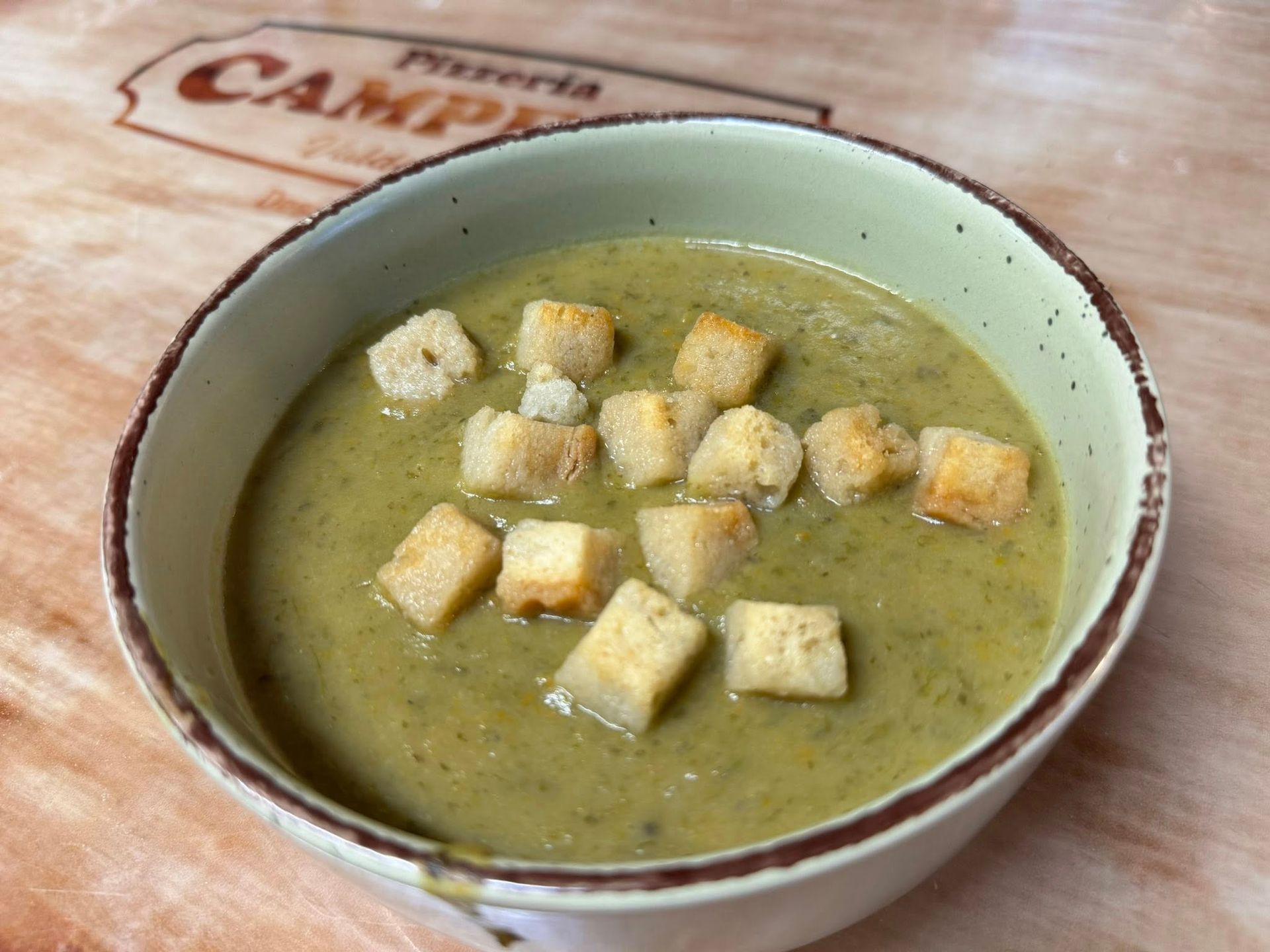 Tazón de sopa verde con crutones.