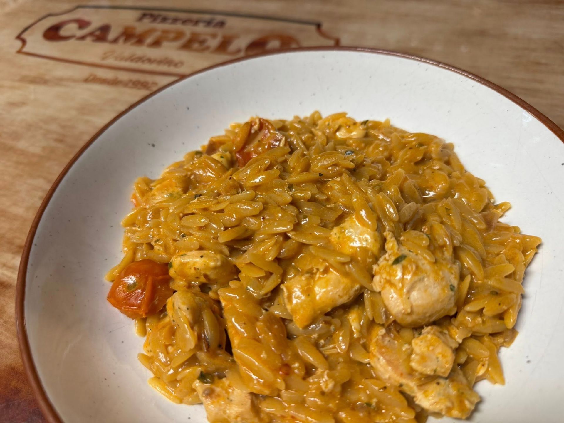 Plato de pasta con pollo y tomates en salsa cremosa, servido en un plato blanco.