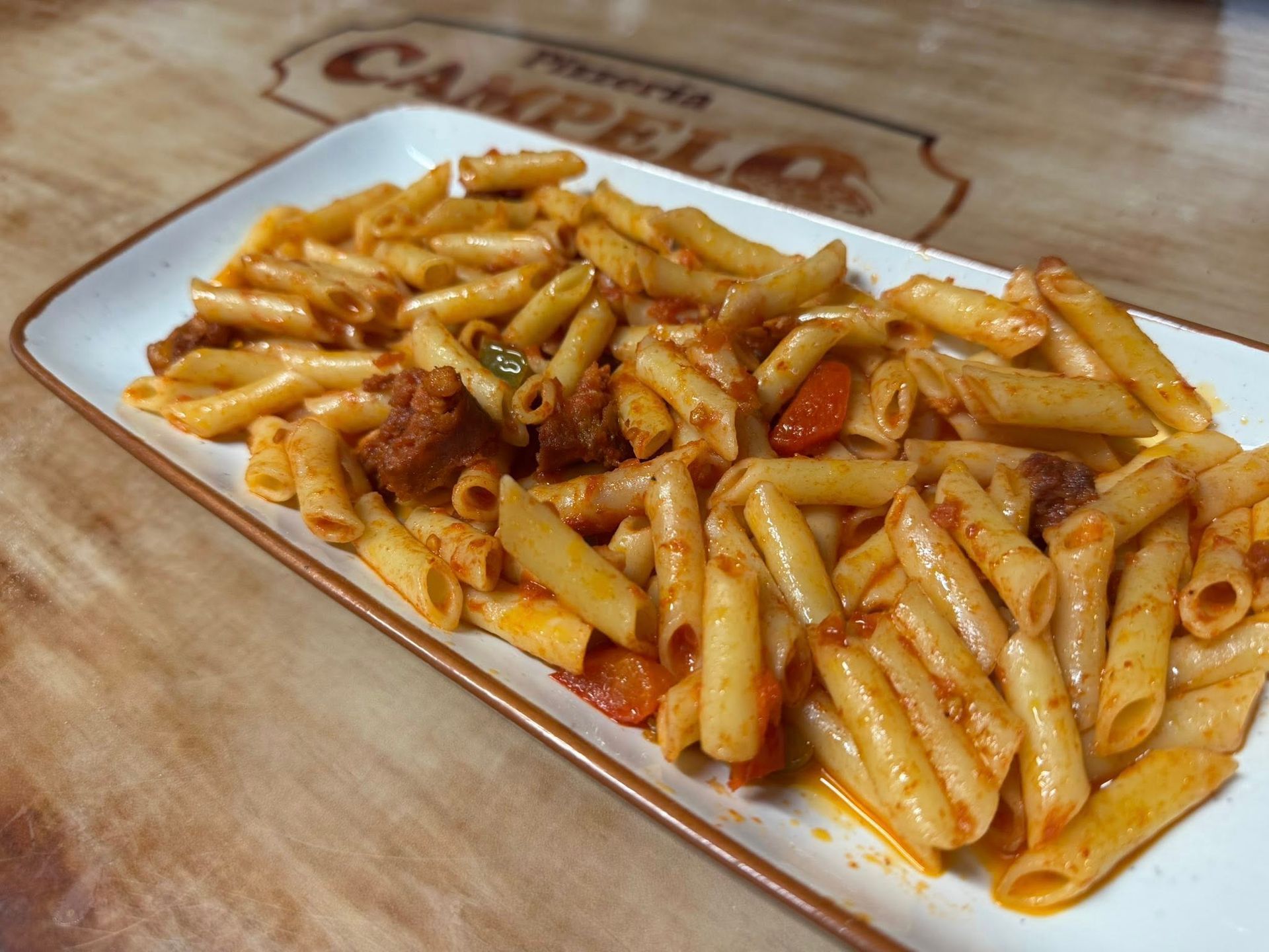 Plato de pasta con salsa de tomate, en plato rectangular.