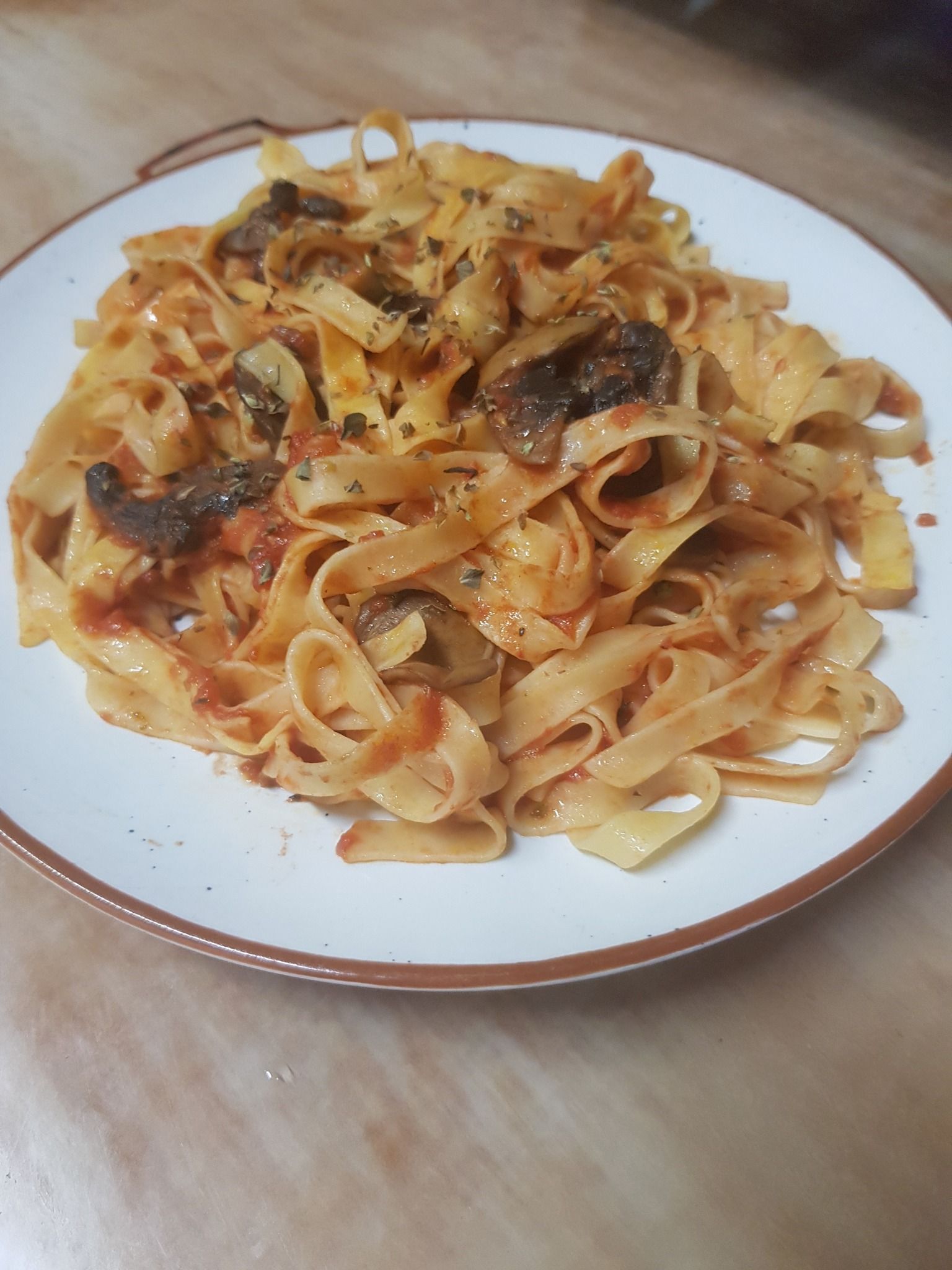 Plato de pasta con champiñones y salsa de tomate en un plato blanco.