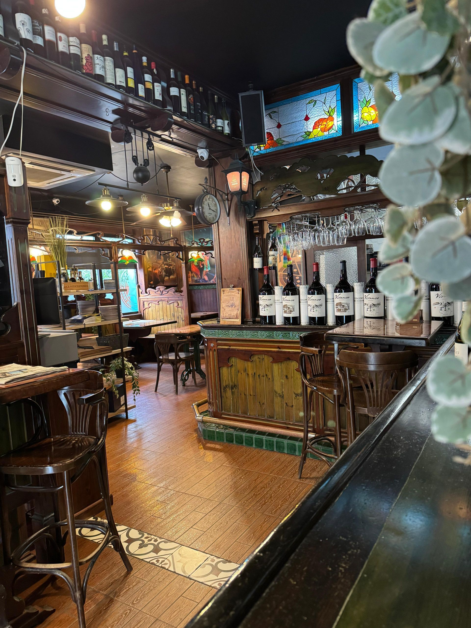 Interior de bar acogedor y rústico con botellas de vino, taburetes de madera e iluminación oscura.