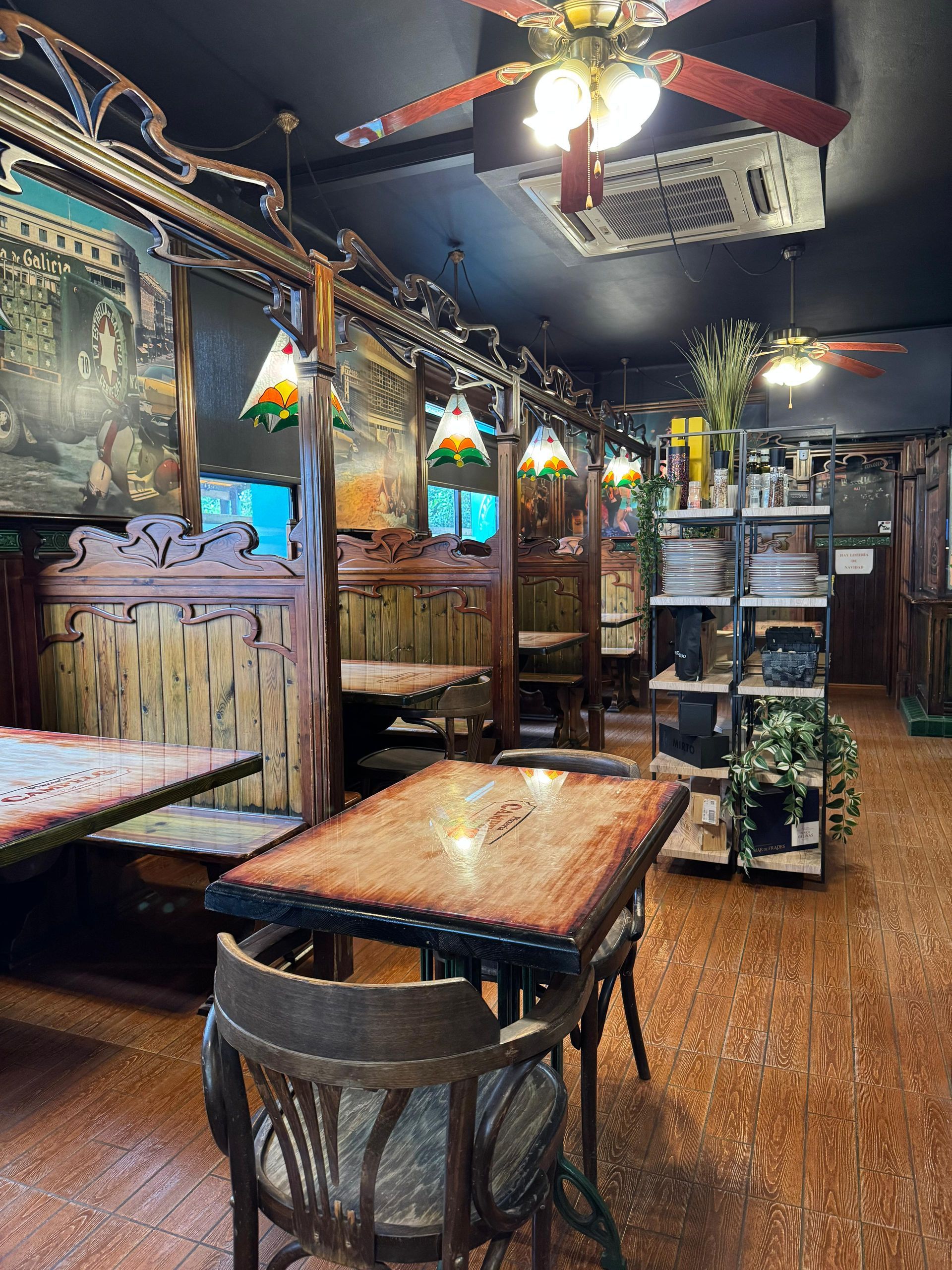 Interior de restaurante rústico con cabinas de madera, mesas, sillas, decoraciones ornamentadas e iluminación tenue.