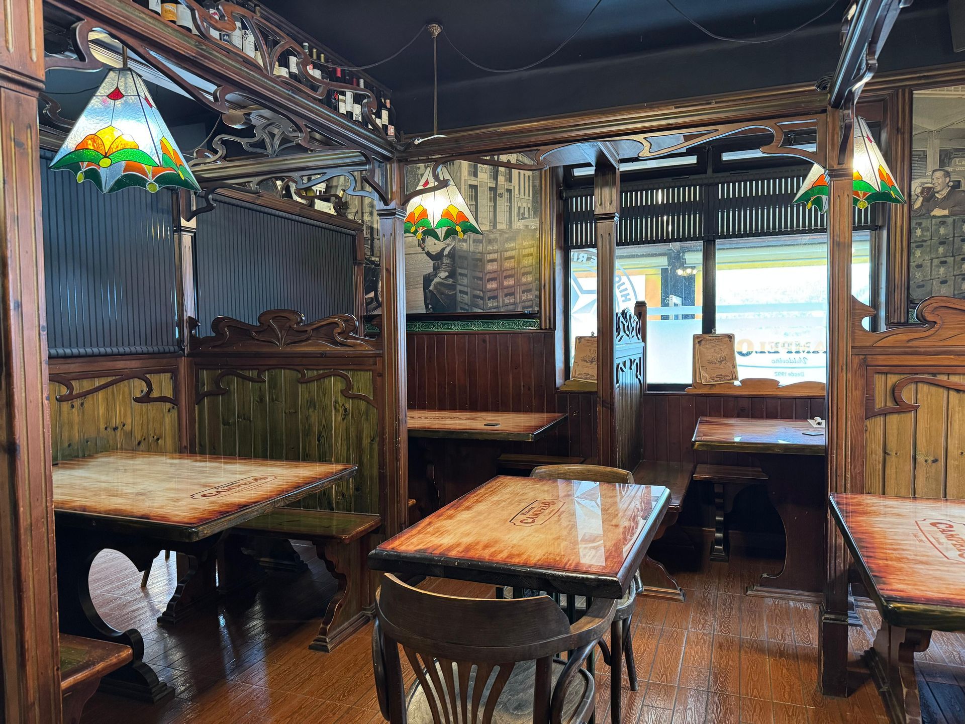 Vista interior de un restaurante rústico con mesas de madera, luces decorativas y paneles de madera oscura.