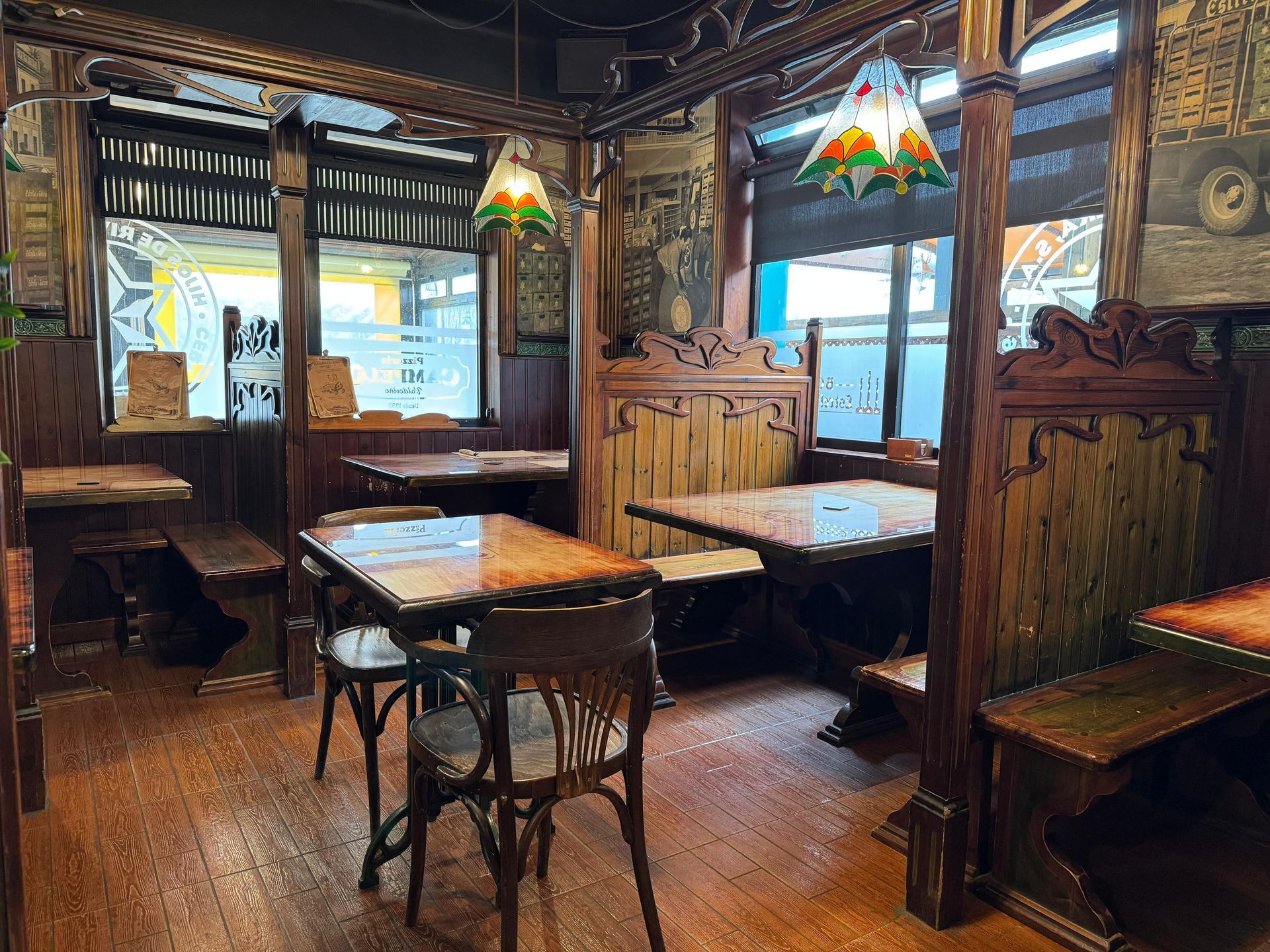 Interior de madera de un restaurante con mesas, sillas y lámparas de vidrieras.