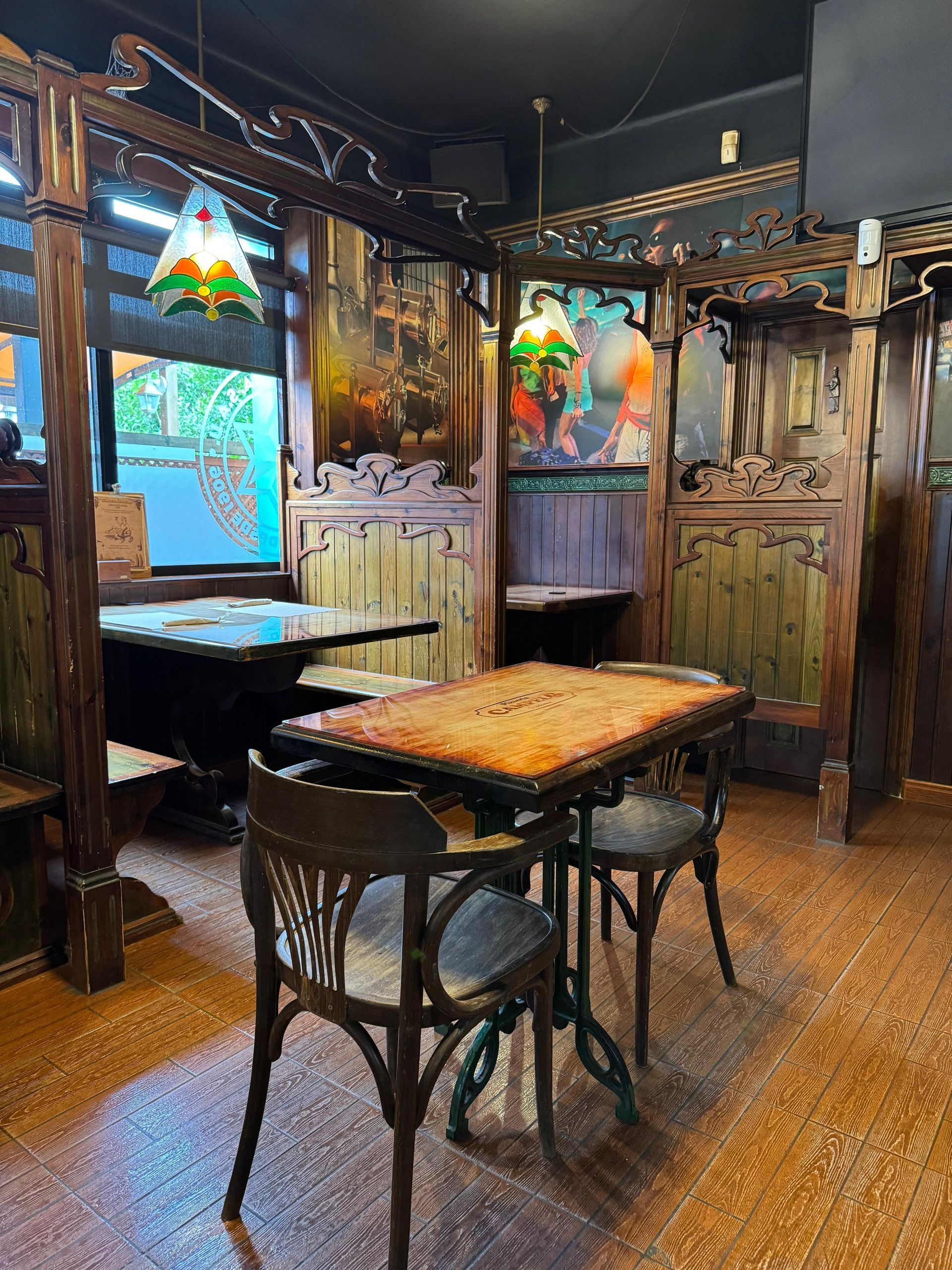 Interior de restaurante con cabinas, mesas y sillas de madera. Iluminación cálida.
