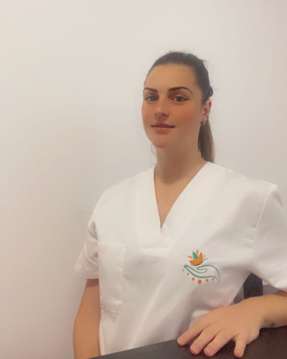 Una mujer con un uniforme blanco está sentada en una mesa.