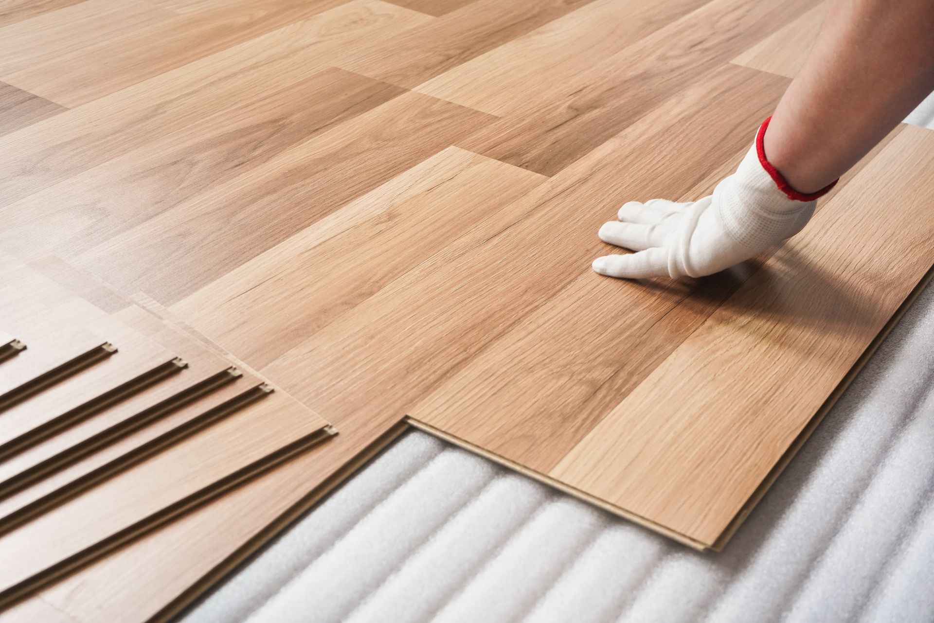 Main gantée installant une lame de parquet stratifié
