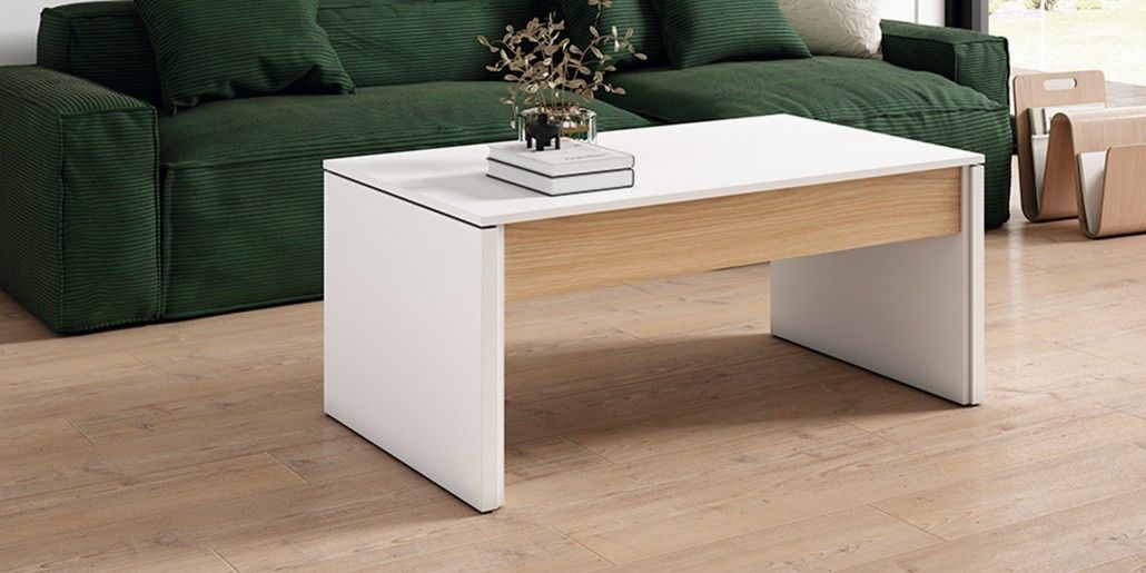 Mesa de centro blanca frente a un sofá verde, con decoración en la mesa, pisos de madera.