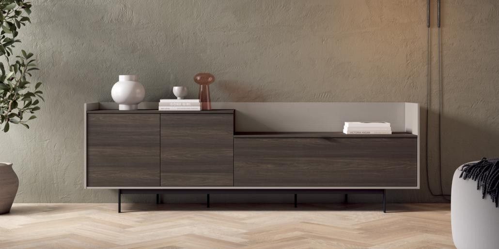 Un aparador de madera moderno con decoración neutra y una planta, contra una pared texturizada.