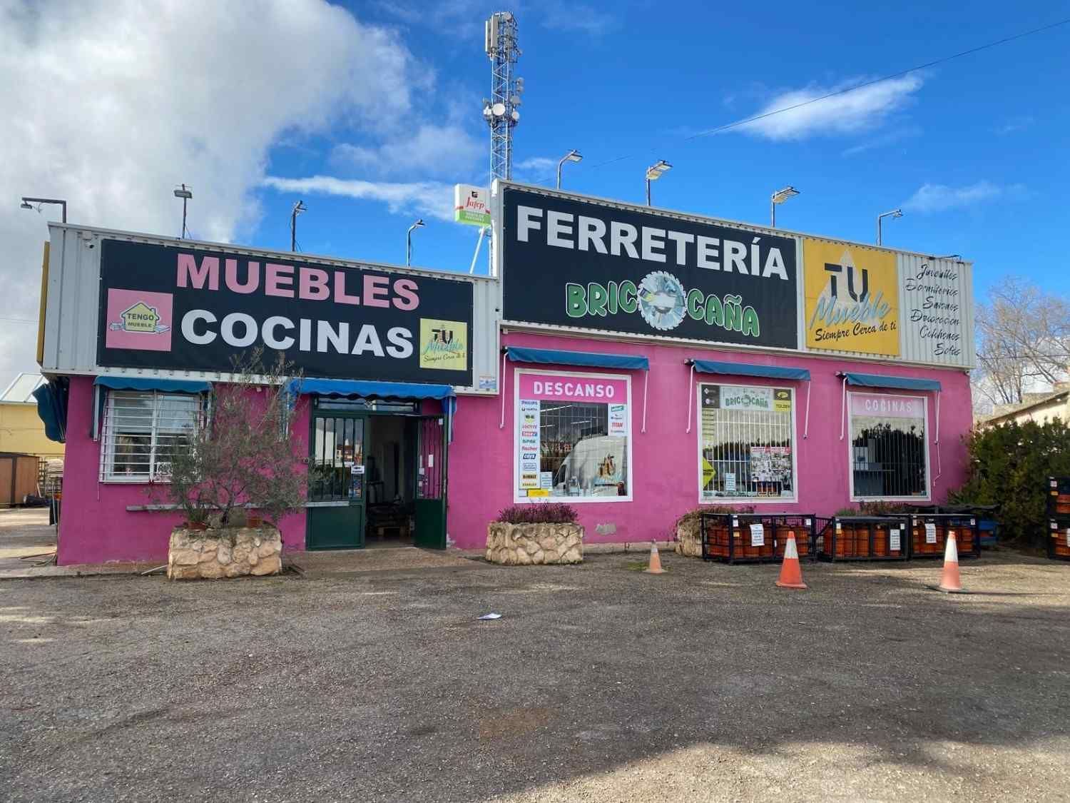 Fachada de un edificio con varios letreros. El exterior es rosa y tiene varios letreros grandes de diferentes negocios.