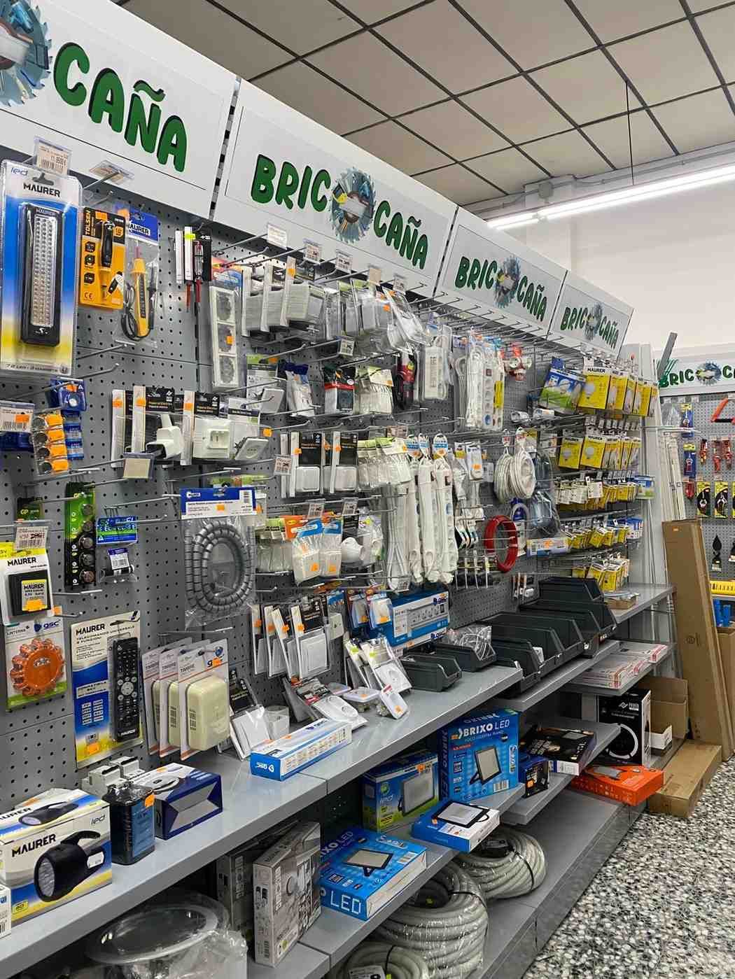 Pasillo de ferretería con estantes que muestran diversos componentes eléctricos y herramientas.