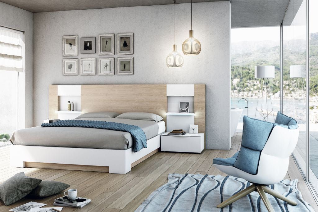 Dormitorio moderno con cama, mesita de noche, sillón y gran ventanal con vista panorámica.