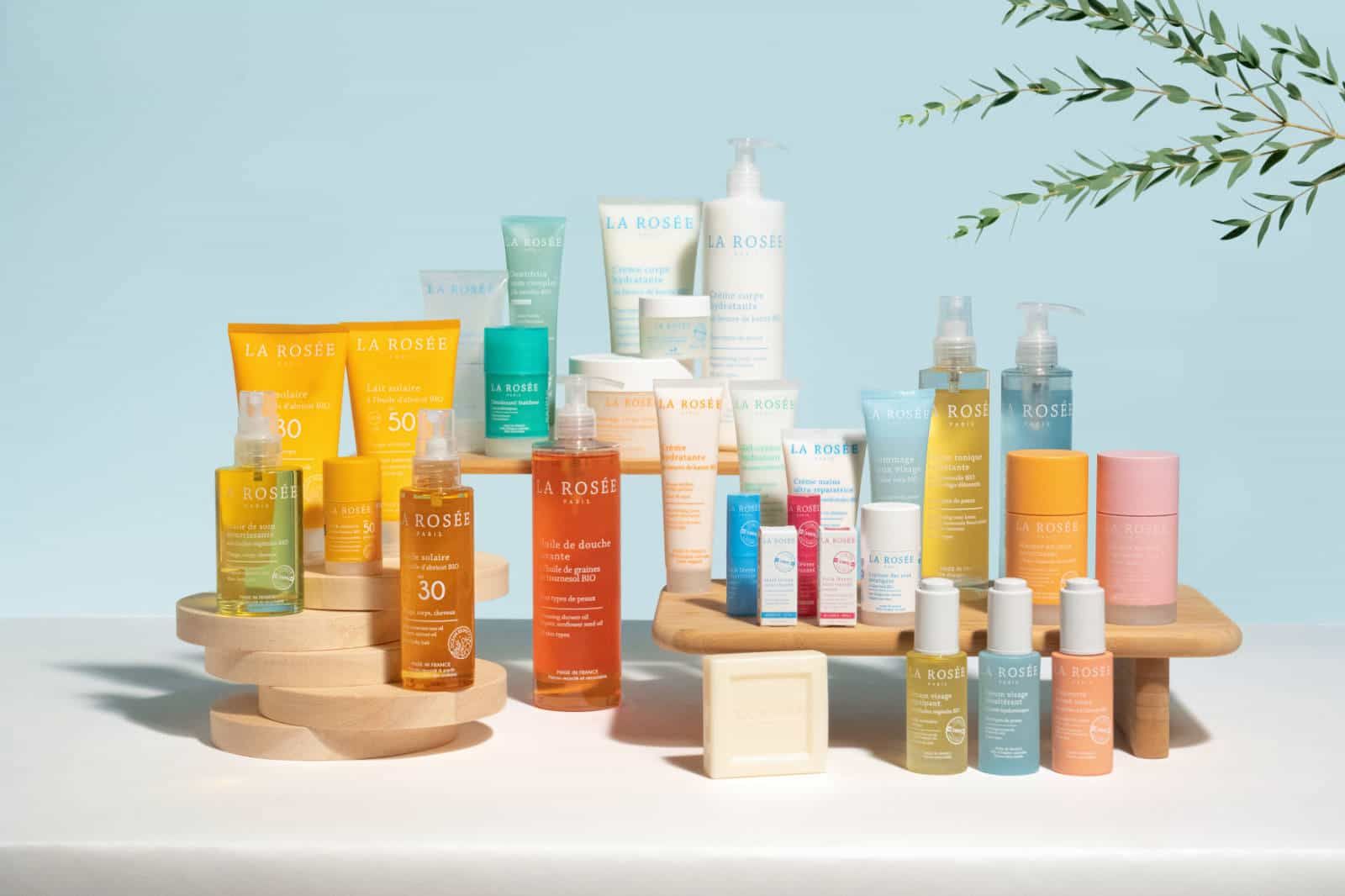 Des produits cosmétiques présentés sur des plateformes en bois sur fond bleu clair, avec divers flacons et tubes