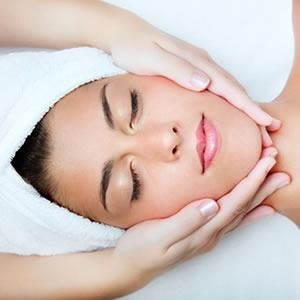 Una mujer con una toalla envuelta alrededor de su cabeza está recibiendo un masaje facial.