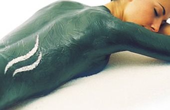 Una mujer está acostada en una cama con la espalda pintada de verde.