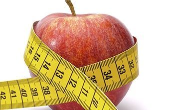 Una manzana roja con una cinta métrica amarilla alrededor.