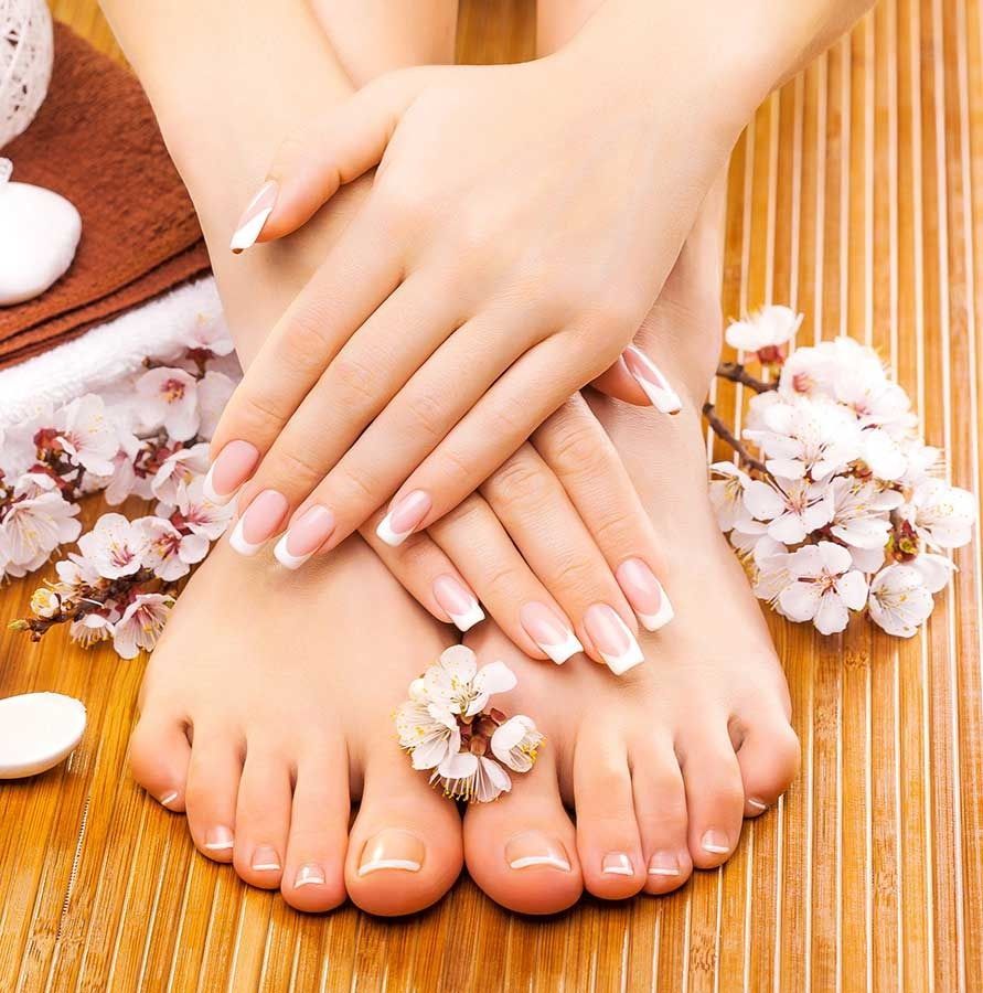 Un primer plano de los pies y las manos de una mujer con flores en el fondo.