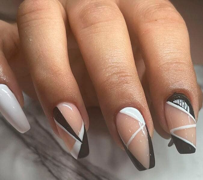 Un primer plano de las uñas de una mujer con un diseño en blanco y negro.
