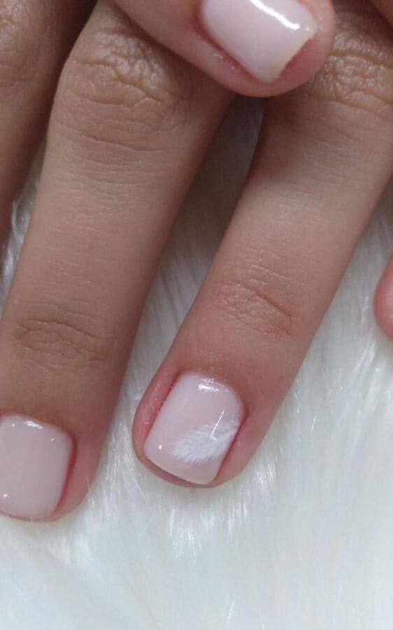 Un primer plano de las uñas de una persona sobre una superficie blanca.