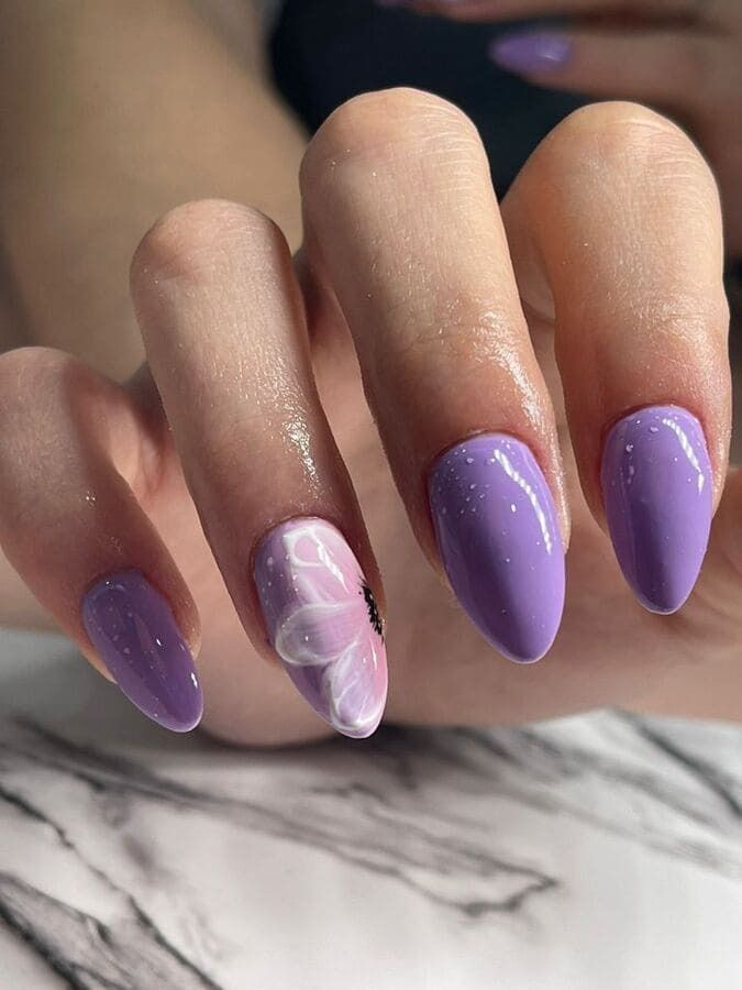 Un primer plano de las uñas moradas de una mujer con un diseño de mariposa.