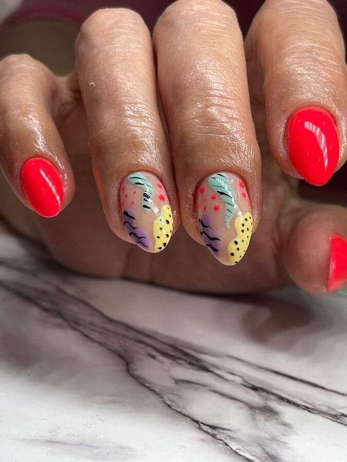 Un primer plano de las uñas de una mujer con esmalte de uñas rojo y un diseño colorido.