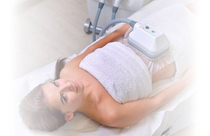 Una mujer está acostada en una cama con una máquina sobre su estómago.