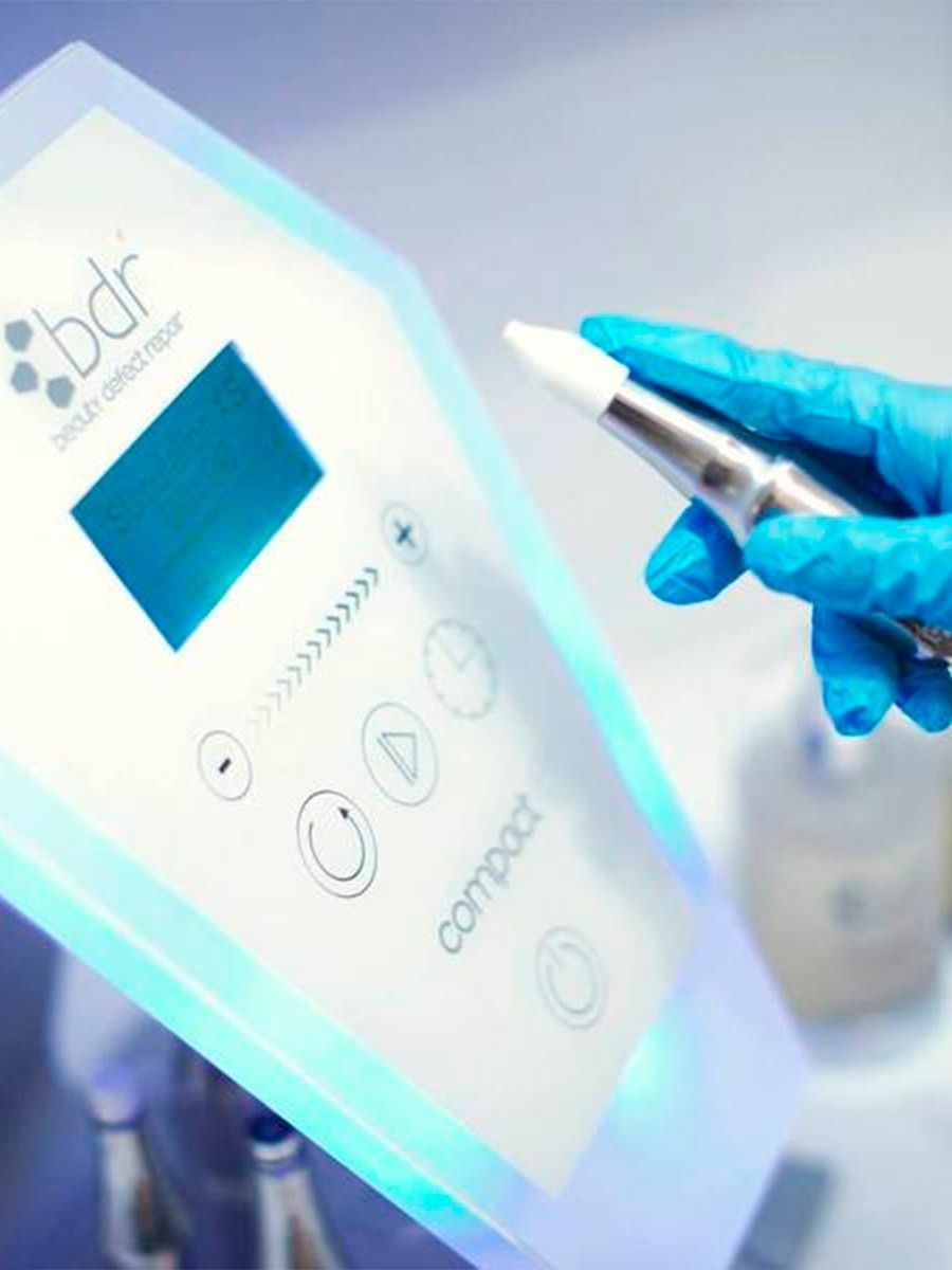 Una persona que lleva guantes azules sostiene un bolígrafo delante de una máquina.