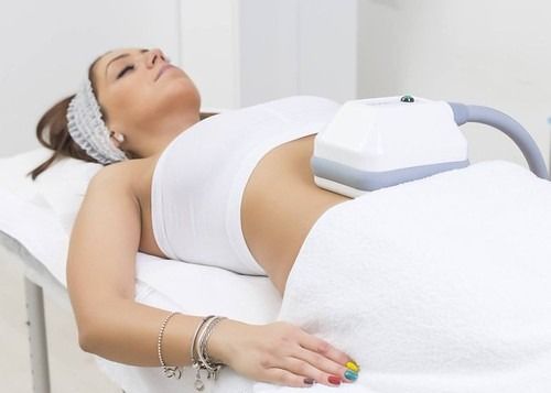 Una mujer está acostada en una cama con una máquina sobre su estómago.