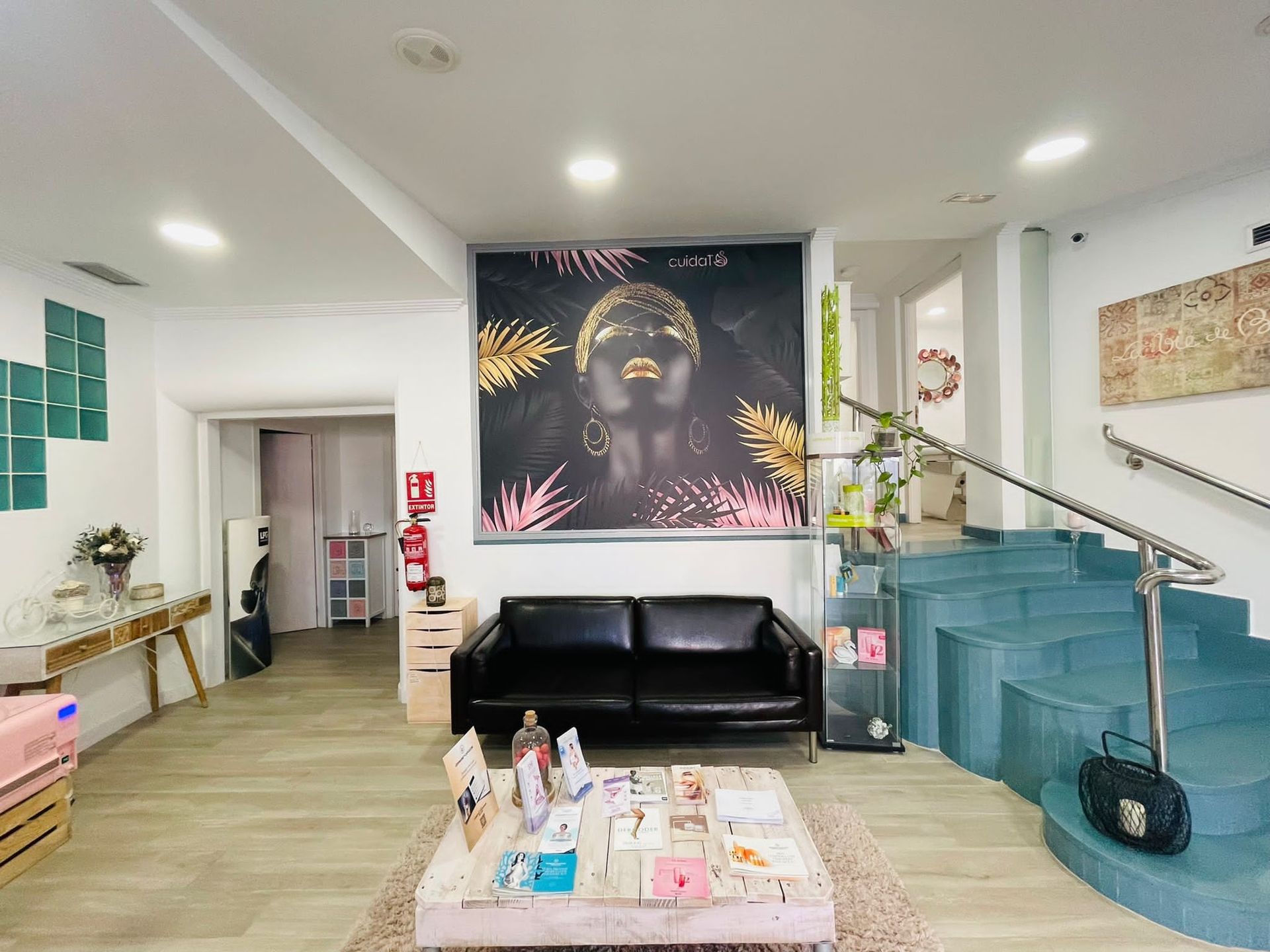 Una sala de estar con un sofá, una mesa, escaleras y un cuadro en la pared.