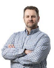 Siniruudullinen mies seisoo kädet ristissä valkoista taustaa vasten