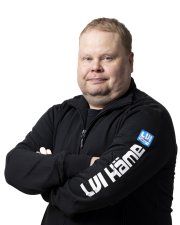 Mies mustassa hupparissa kädet ristissä valkoista taustaa vasten