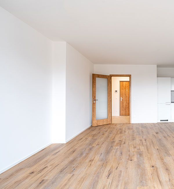 Pièce vide avec parquet et murs blancs. 