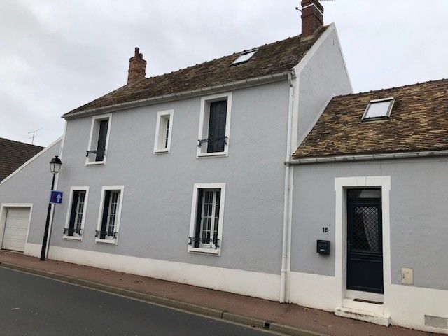 Maison bleu clair à deux étages avec volets foncés, porte noire et toit marron.