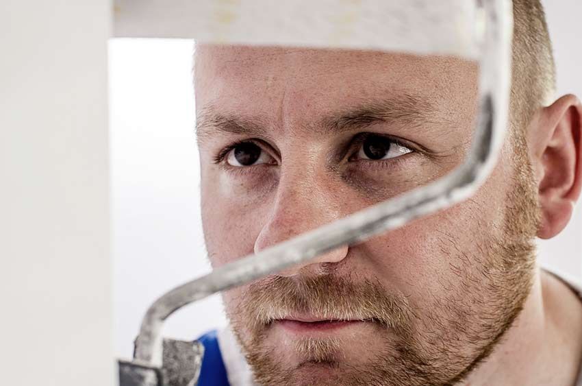 Un homme à la barbe rousse se concentre intensément sur un rouleau à peinture.
