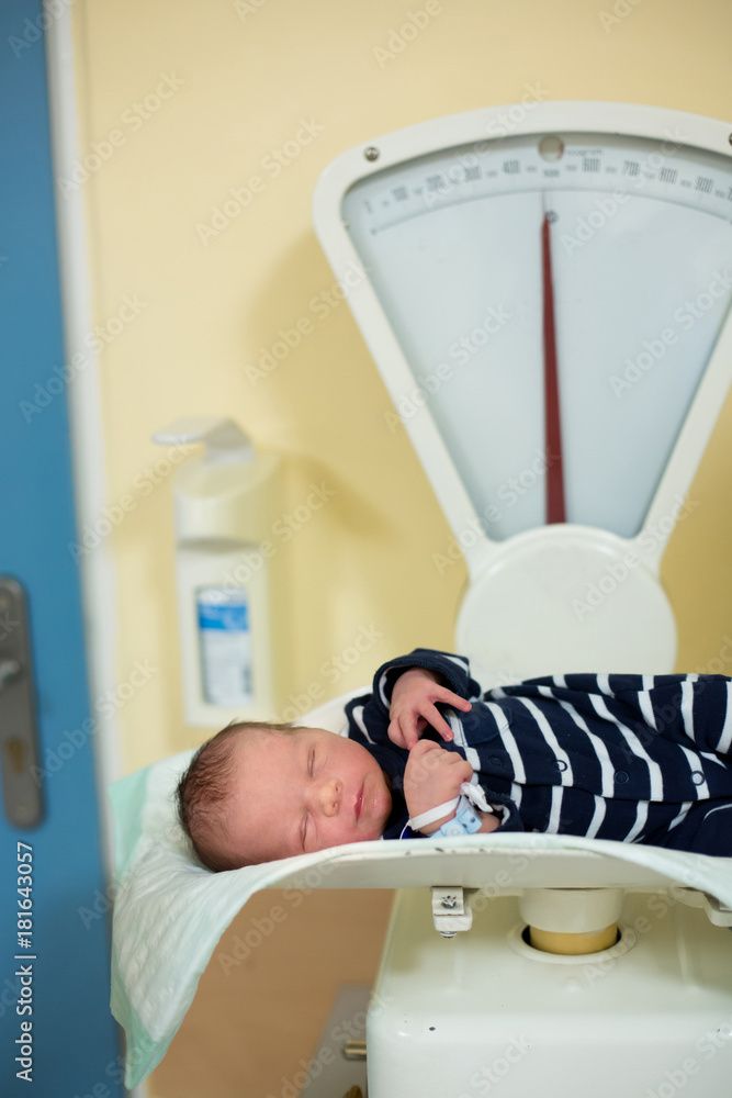 Un neonato è sdraiato su una bilancia.