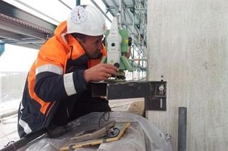 Ein Mann mit Schutzhelm arbeitet an einer Maschine.