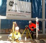 Zwei Männer arbeiten vor einem Schild mit der Aufschrift GE Energy Products Europe