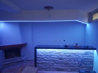Una sala de estar con chimenea y un bar con luces azules.