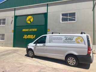 Una camioneta blanca está estacionada frente a un edificio con una puerta verde.