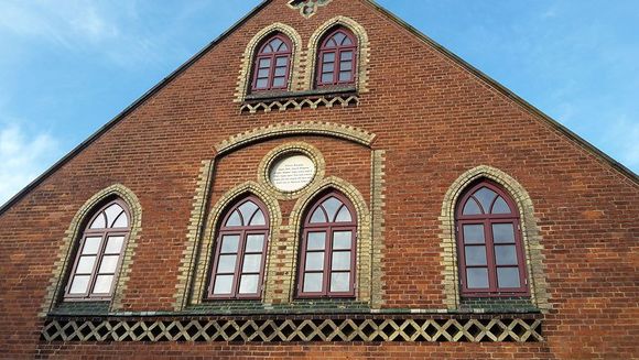 Ein Backsteingebäude mit Bogenfenstern und einer Uhr darauf.