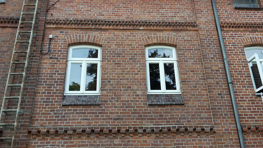 Ein Backsteingebäude mit zwei Fenstern und einer Feuerleiter